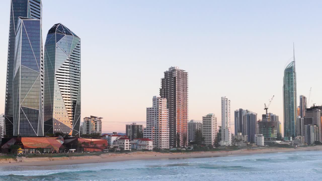 A serene view of Gold Coast's skyline during sunset, highlighting modern architecture and calm ocean waters under soft, natural lighting