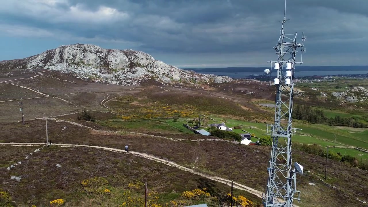 Vista aerea che sorvola un'antenna di una torre di telecomunicazioni che domina la campagna del monte Holyhead.