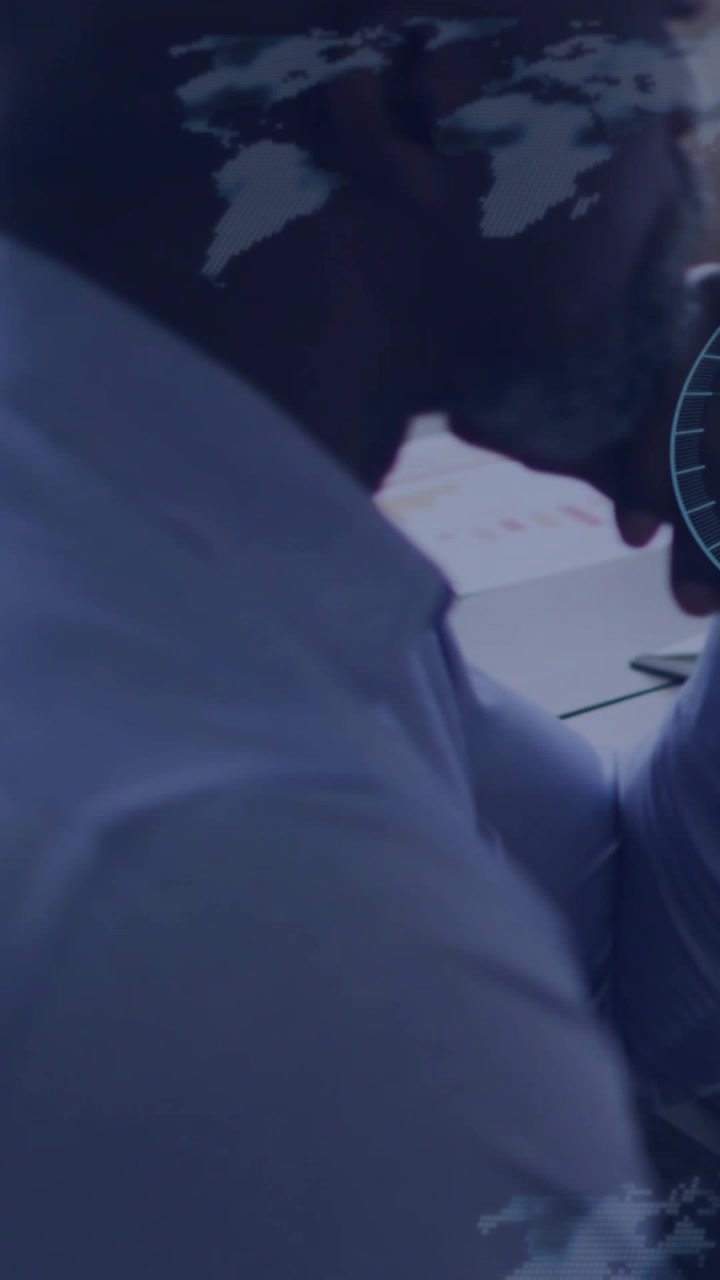 Vertical video: Studying man in shirt and tie reviewing papers at desk as overlays animating