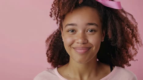 young woman wearing pink ribbon symbolizing breast cancer awareness, radiating hope and positivity against pink background, representing strength and resilience of survivors