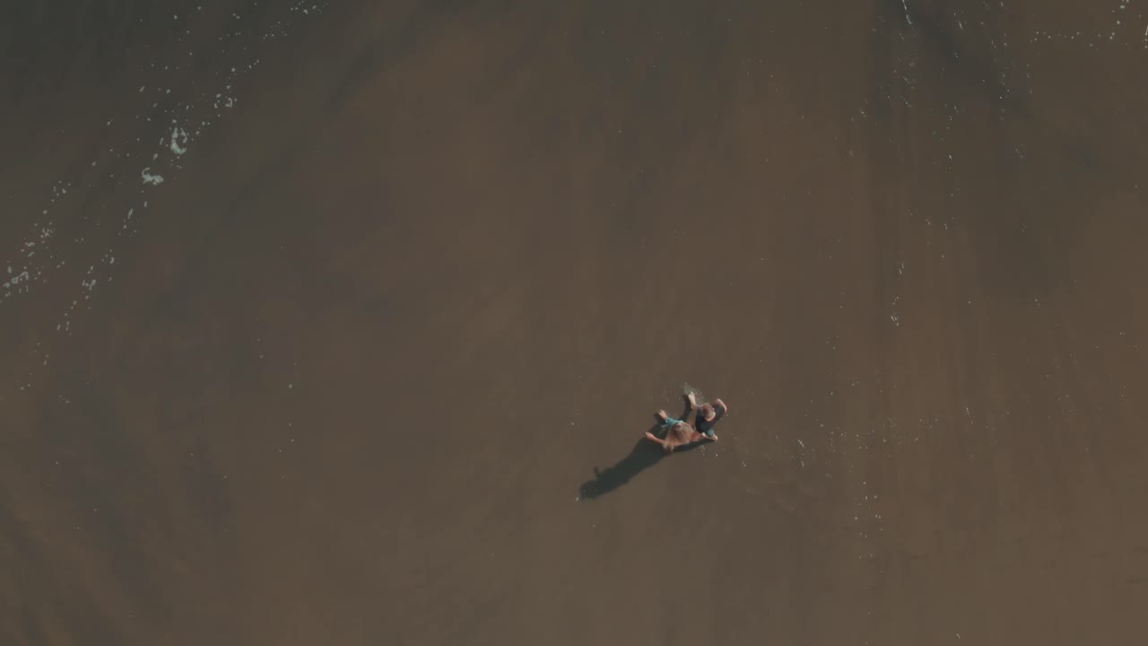 4k Aerial wave coming on people on black sand beach Drone overhead shot