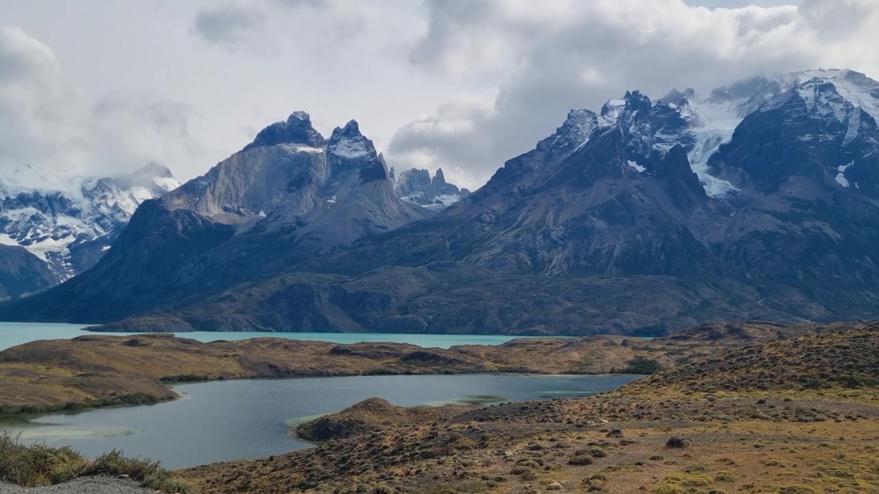 Paesaggio patagonico remoto nel Parco Nazionale Torres del Paine, Cile, con le acque turchesi del Lago Pehoé e imponenti cime montuose. Una scena selvaggia mozzafiato sotto cieli mutevoli.