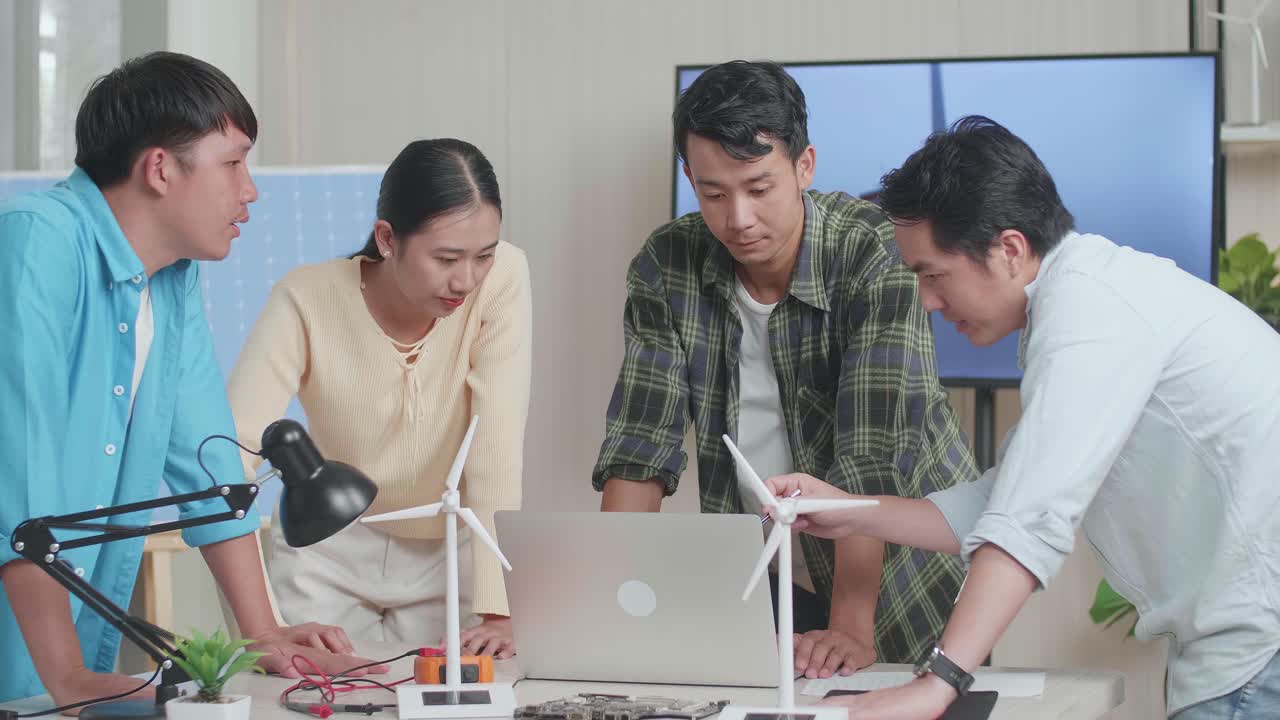 아시아 엔지니어 그룹은 풍력 터빈과 함께 사무실에서 노트북 작업에 대해 논의합니다.