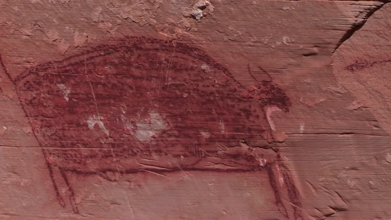 медленная панорама загадочных петроглифов в юго-западной пустыне сша, на которых изображен ранний человек, убивающий или охотящийся с луком и стрелами.