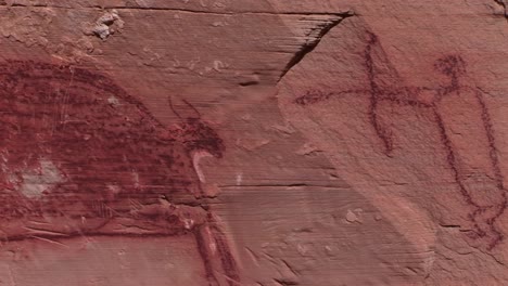 a slow pan across mysterious petroglyphs in the southwest desert of the usa showing early man killing or hunting with a bow and arrow