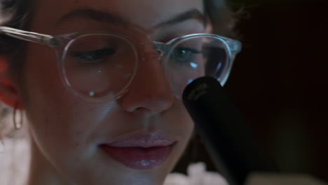 a young beautiful female scientist in glasses looks through the eyepiece of the microscope in the laboratory