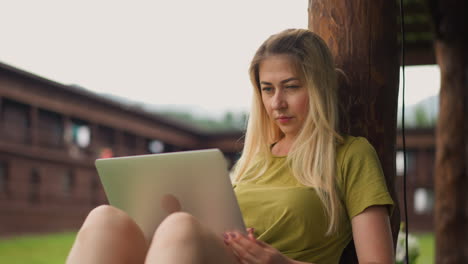 pretty lady watches video via laptop on restaurant terrace