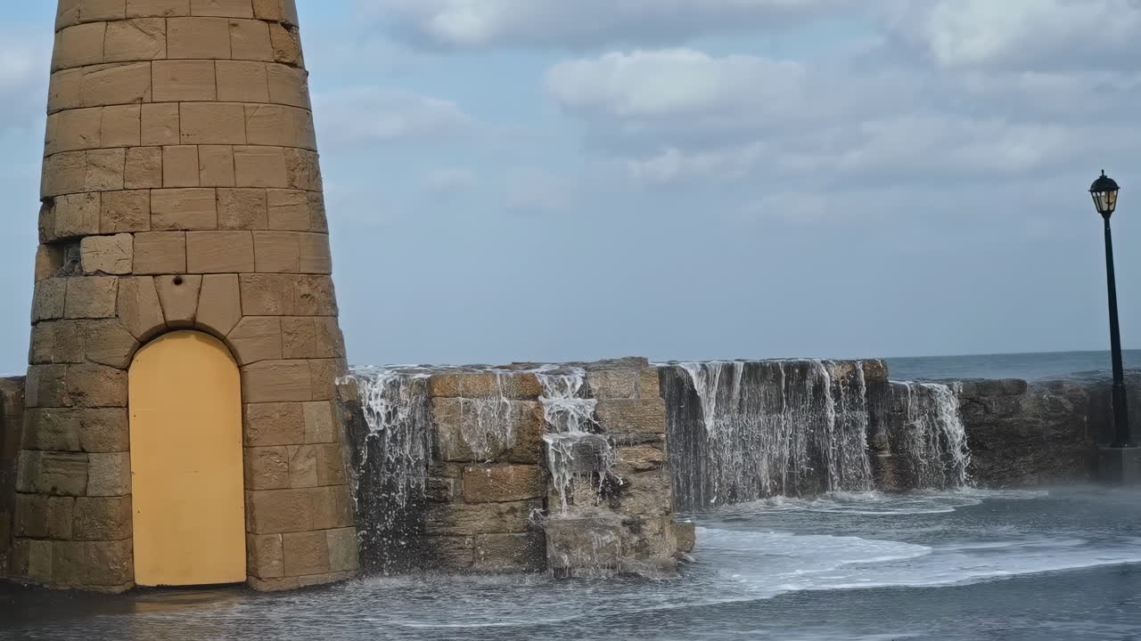 Water splashing over the Girne Historic Lighthouse on the shore in Kyrenia, Cyprus