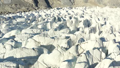 aerial drone flying over the deep crevasses in the cold and white passu glacier located in hunza pakistan during summer