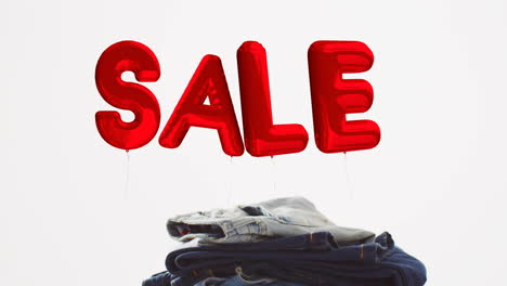 animation of sale red balloon text over denim trousers on white background