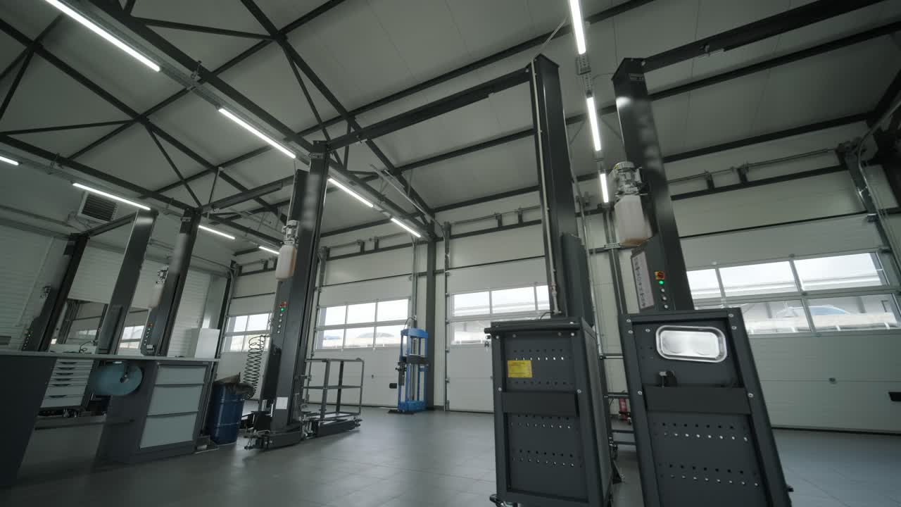 Spacious automotive workshop with vehicle lifts, tools, workstations, and mechanics working. Bright industrial space designed for car repair and maintenance