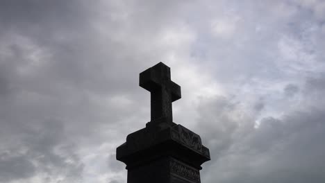 Lapso-De-Tiempo-De-Nubes-Grises-Oscuras-Que-Pasan-Sobre-El-Monumento-Conmemorativo-De-La-Lápida-Del-Crucifijo-Religioso-Cristiano-En-El-Espeluznante-Cementerio-Aterrador-4k