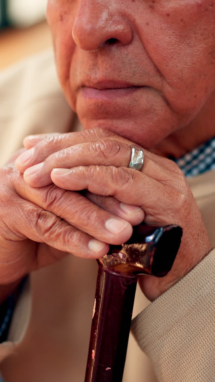 Close-up of Elderly Person's Hands Resting on Walking Stick