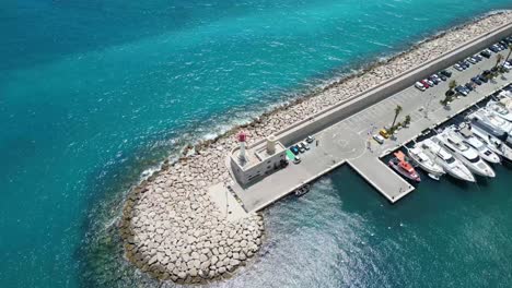 breakwater and port lighthouse for the marina at menton southern france seen from above, aerial pan right reveal shot