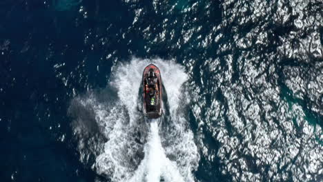 A-boat-speeds-through-the-sparkling-blue-waters-of-Sardinia,-creating-white-waves-behind-it