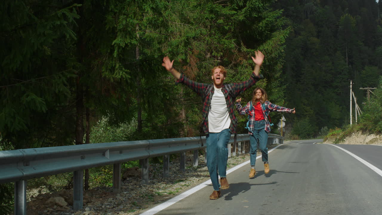 autostopistas llenos de alegría agitando las manos en la carretera de la montaña.