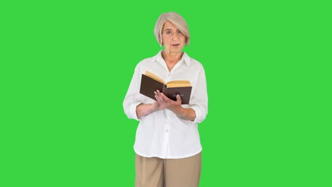 senior lady woman reading old book out loud on a green screen, chroma key