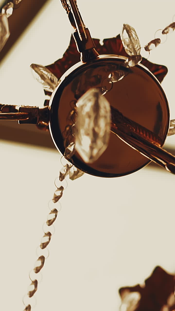 CU, slow motion: stylish designer golden metal luster decorated with shiny glass stones hangs on ceiling in spacious room closeup low angle shot