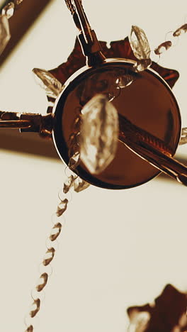 cu, slow motion: stylish designer golden metal luster decorated with shiny glass stones hangs on ceiling in spacious room closeup low angle shot