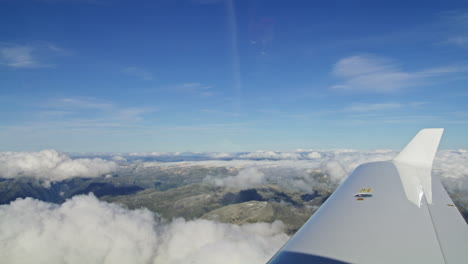 looking out of an aeroplane window down onto clouds and mountain ranges