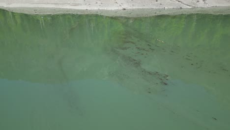 Muddy-Water-Surface-In-Klöntalersee-Glarus-Kanton-Lake-In-Switzerland--Drone-View