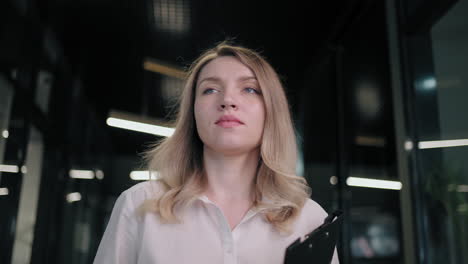 beautiful business woman walking in office corridor. businesswoman walking on meeting in office interior. cheerful professional going on meetup in business center hallway