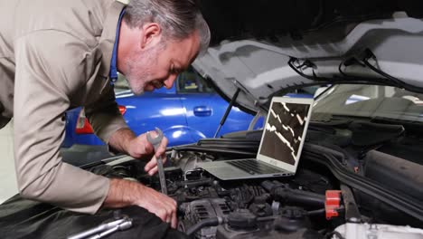 Mechanic-using-laptop-while-servicing-a-car-engine