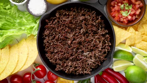 Ingredients-for-Chili-con-carne-in-frying-iron-pan-on-white-wooden-table