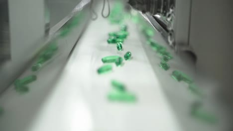 focused green capsules moving on production line in pharmaceutical pill plant.