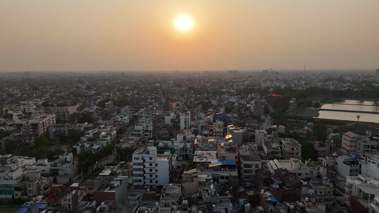 A stunning aerial capture of the sun setting over Varanasi, casting a warm, golden hue over the city's tightly packed neighborhoods and historic temples.