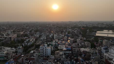 a stunning aerial capture of the sun setting over varanasi, casting a warm, golden hue over the city's tightly packed neighborhoods and historic temples.