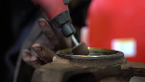 a mechanic with extremely dirty hands is working on a commercial vehicle suspension housing to make it ready for a new bush