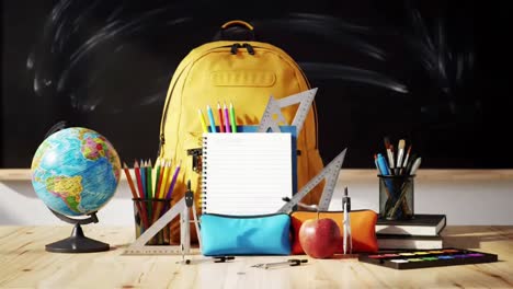 yellow school backpack on a desk with books and art supplies