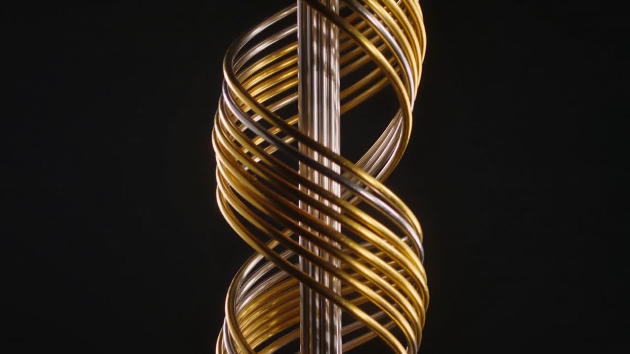Vertical video: Helix assembly rotating on motor spin showing silver rod and gold bands for design