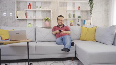 joven enano discapacitado positivo en casa mirando felizmente el teléfono sonriendo y descansando.