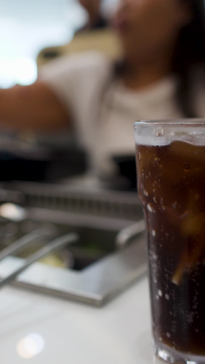 Primo piano di una bibita fredda con ghiaccio in un ristorante affollato