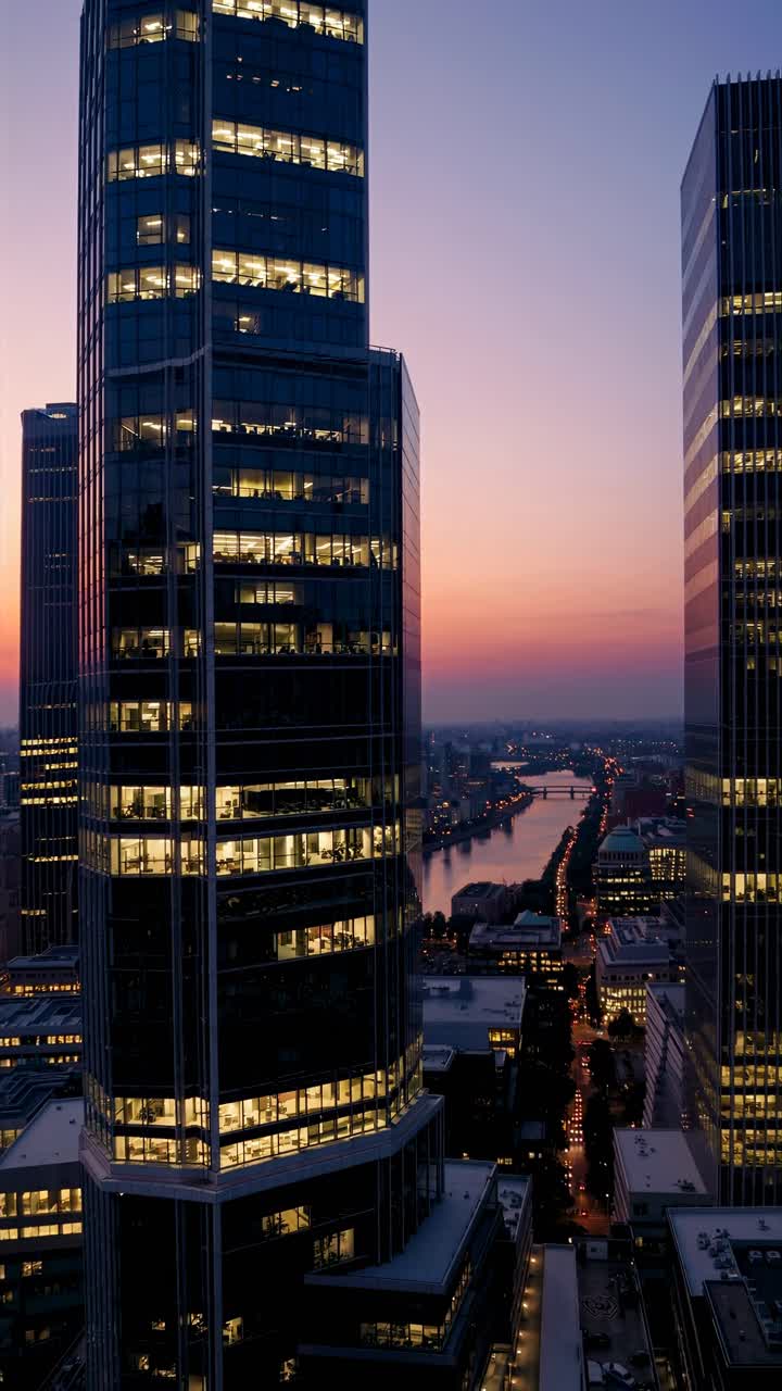Aerial video view of skyscrapers at sunset, capturing urban architecture and a river