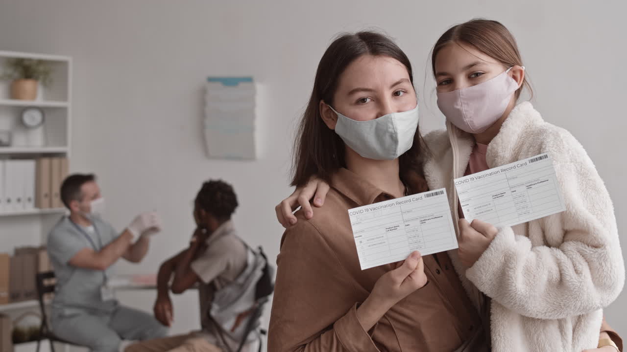 Mother and Daughter Showing Vaccination Cards