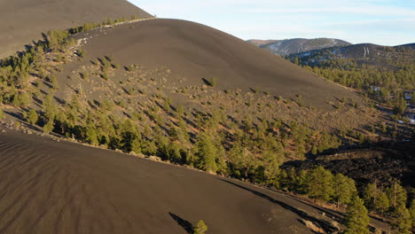 drone flight over scarce vegetation on steep dry sandy volcanic cinder cone mountain