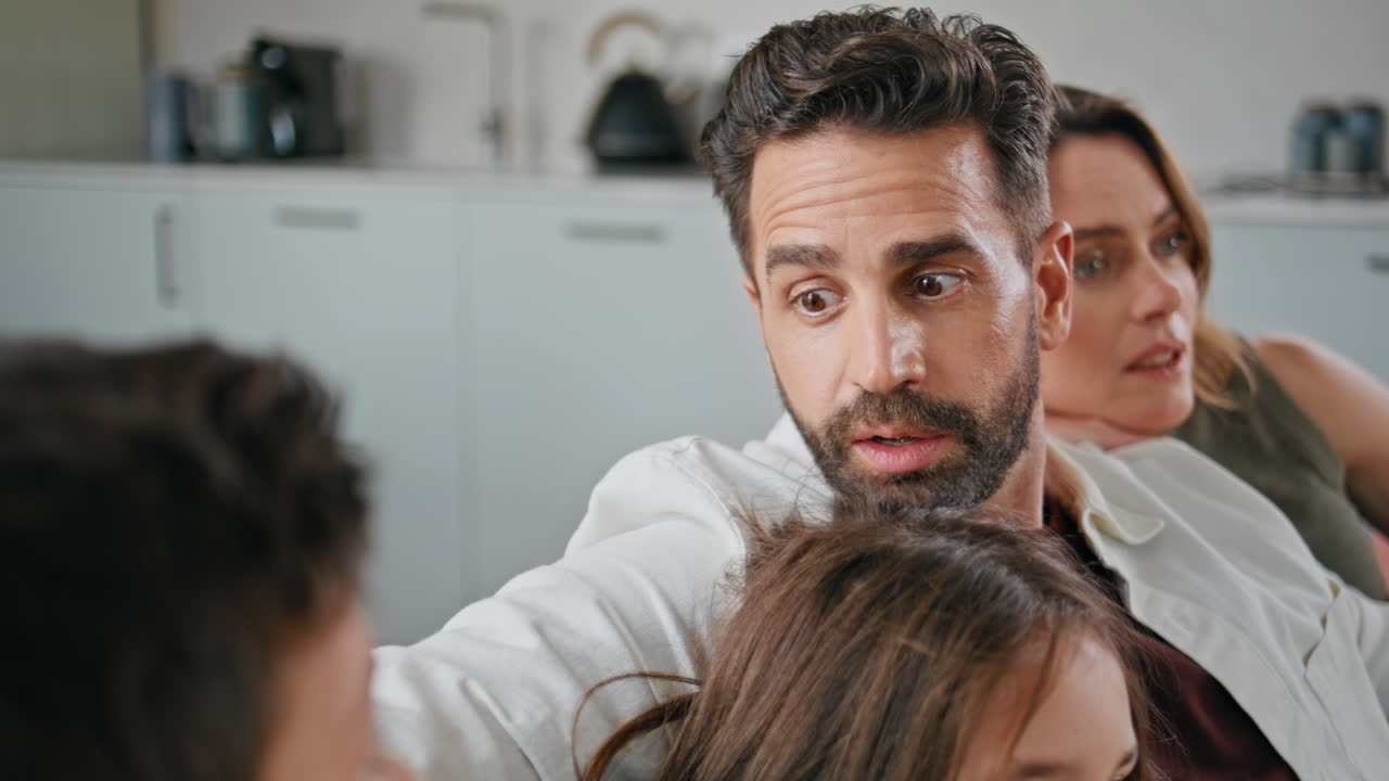 Bearded father talking son relaxing with family on sofa closeup. Parents kids