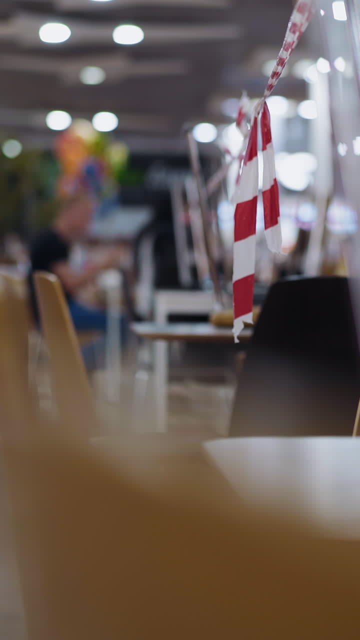 Blurry restaurant closed for coronavirus quarantine with stacked furniture wrapped with warning strip in contemporary shopping mall close view