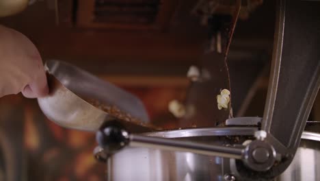woman pouring corn kernels in popcorn machine. process of popcorn production