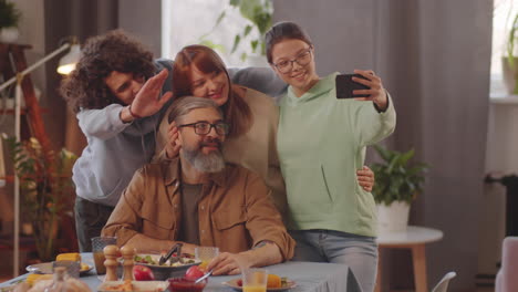 familia alegre tomando selfies con el teléfono inteligente en la cena