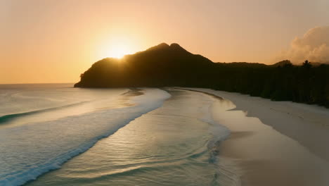 tropical beach at sunset or sunrise with silhouetted mountain
