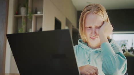 a teenage girl is crying near a computer monitor.