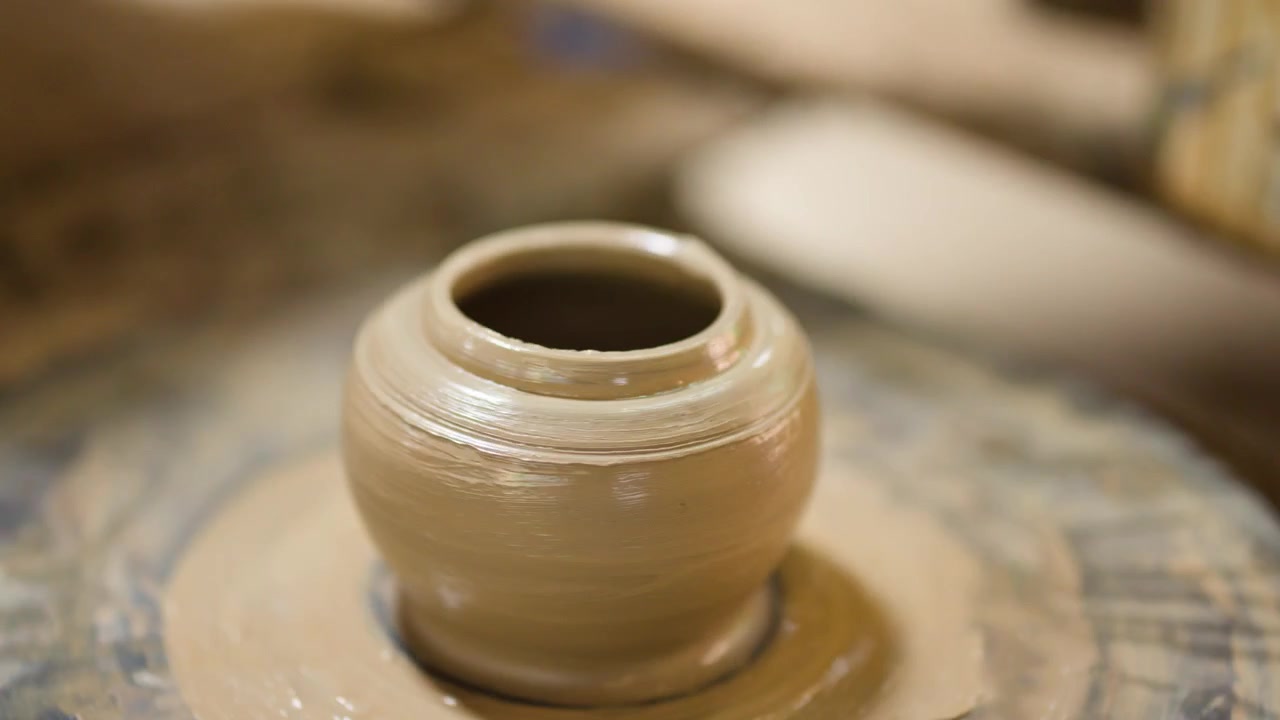 Close-up of skilled artisan hands molding a ceramic clay pot on a spinning potter's wheel.