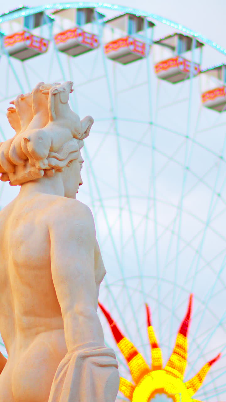 Nice, France - December 8, 2024: Apollo statue in the Fontaine du Soleil at Place Massena with a ferris wheel on the background. Vertical