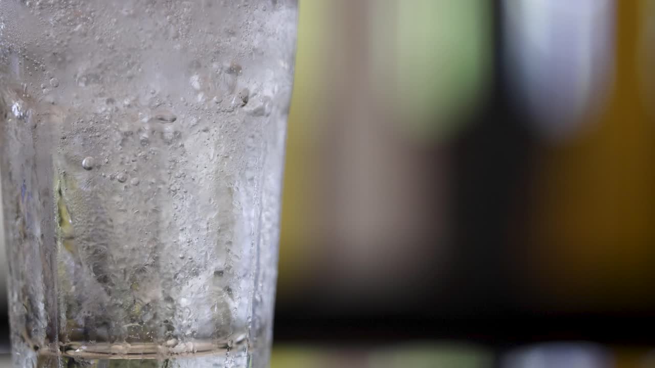 A close-up of soda being poured into a glass, highlighting bubbling carbonation with a shallow depth of field