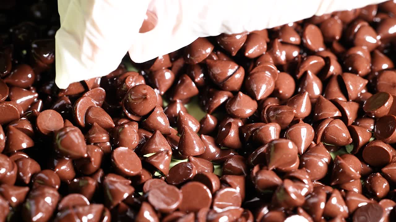 manos con guantes clasificando con cuidado las fichas de chocolate