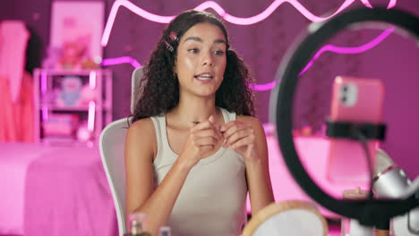 woman creating makeup tutorial in pink lit bedroom